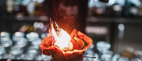 A person holding a lit candle in a glass holder.