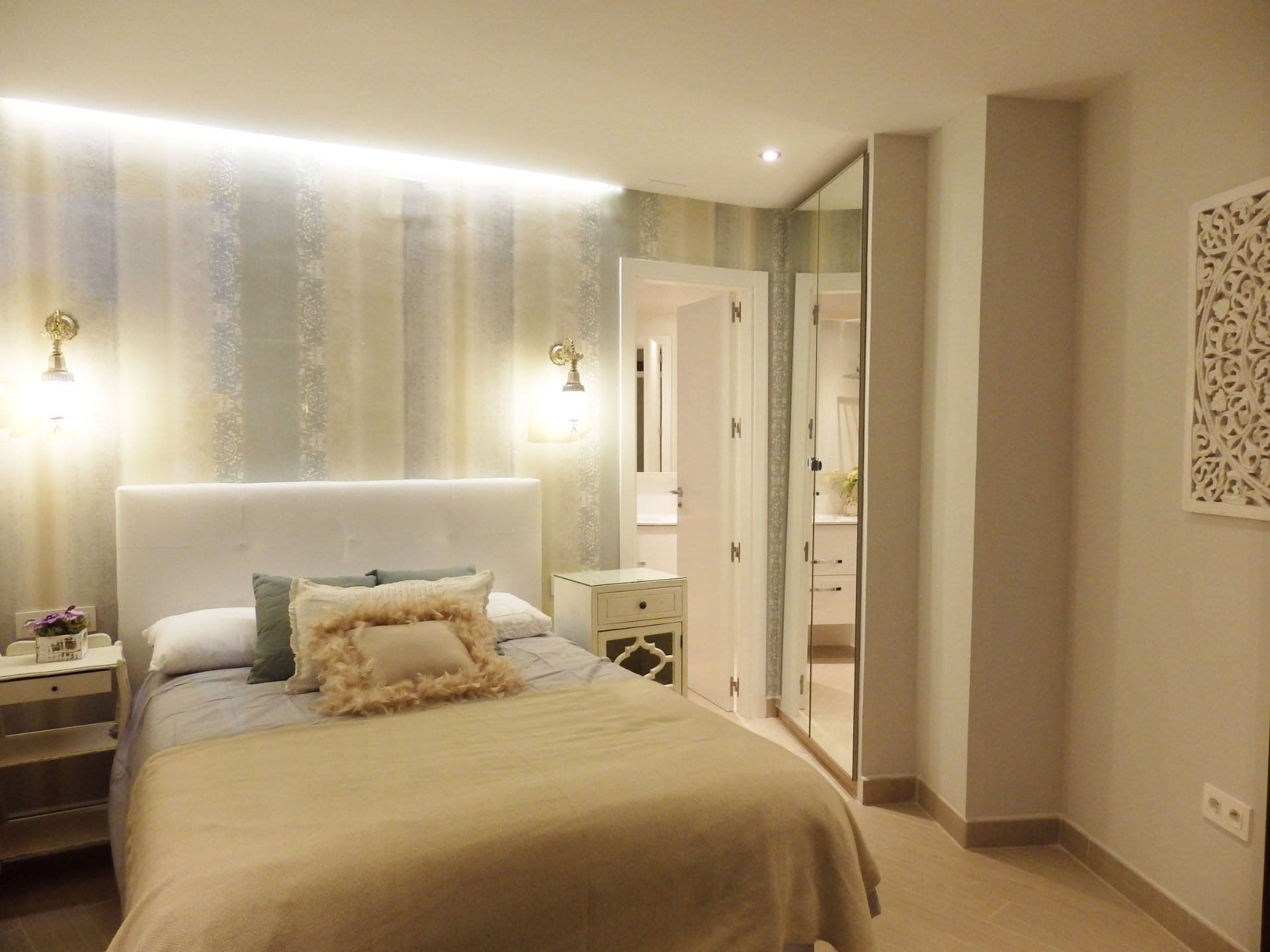 A bedroom with a large bed, nightstands, a dresser, and a walk-in closet.