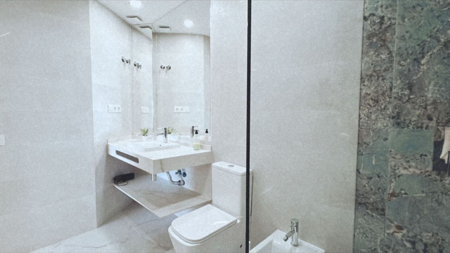A modern bathroom with a large mirror, a sink, a toilet, and a shower area.