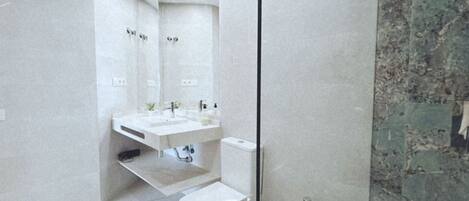 A modern bathroom with a large mirror, a sink, a toilet, and a shower area.