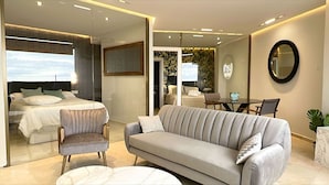 A modern hotel room with a bed, a sofa, a chair, a dining table, and a mirror. - Waterfront Santa Clara Apartments (Torremolinos)