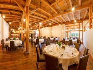 A restaurant with round tables set for dining, wooden beams on the ceiling, and large windows allowing natural light. - ACANTUS Hotel (Weisendorf)