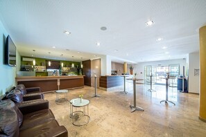 A hotel lobby with a reception desk, seating area, and a view of the city. - ACANTUS Hotel (Weisendorf)