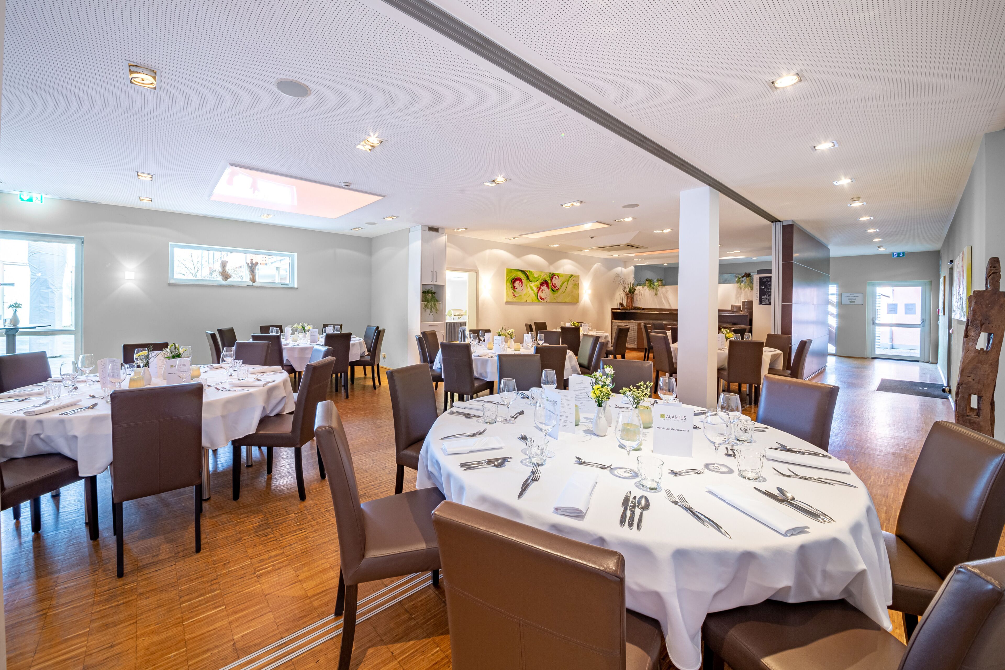Un vaste espace dédié à la salle à manger, avec des tables rondes, des chaises et un design moderne au niveau du plafond.