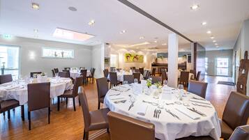 Un vaste espace dédié à la salle à manger, avec des tables rondes, des chaises et un design moderne au niveau du plafond.