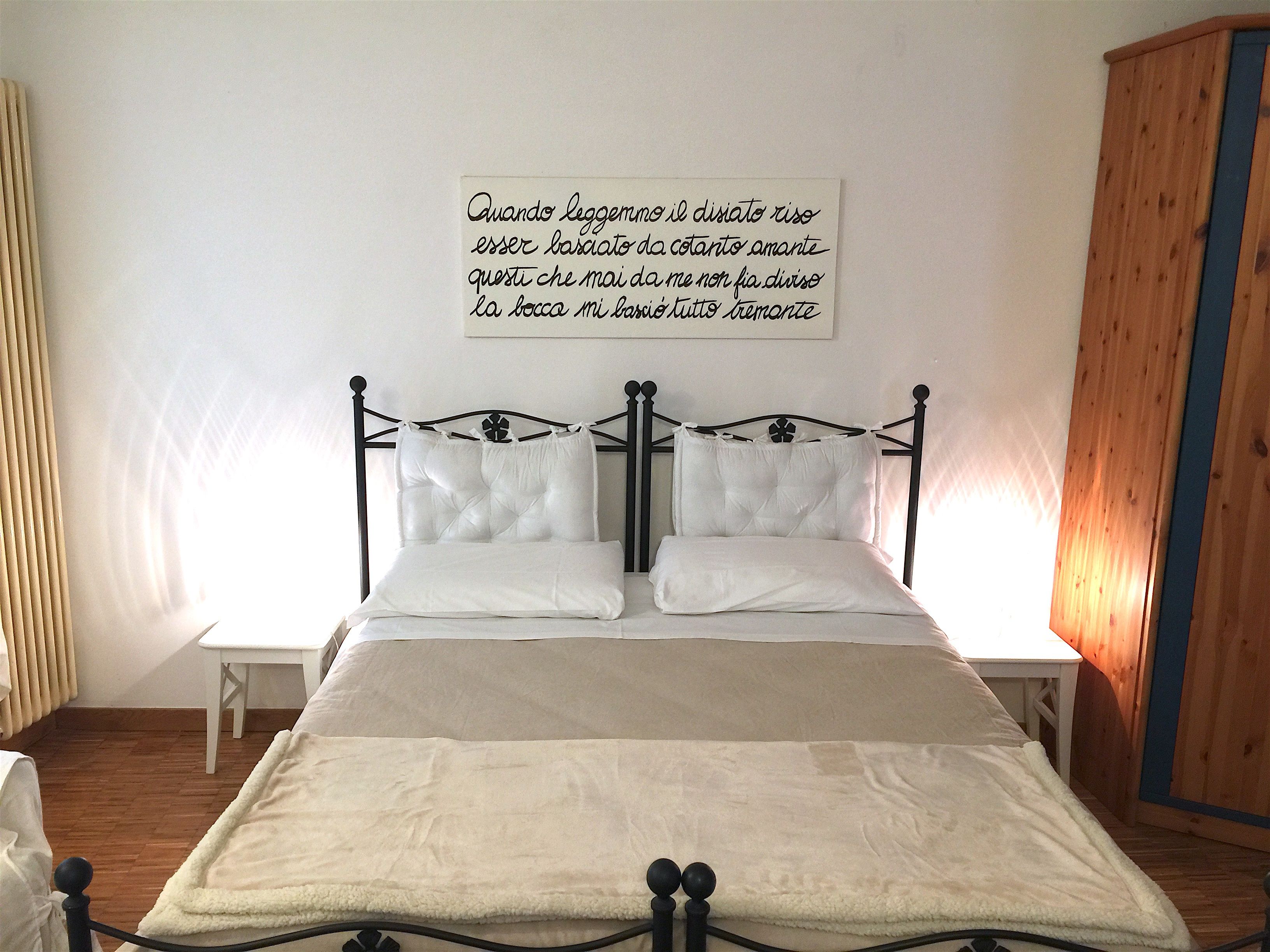 A neatly made bed with white linens and a decorative pillow.