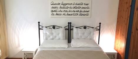 A neatly made bed with white linens and a decorative pillow.