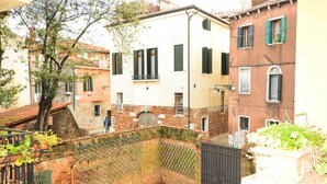 A courtyard with a brick wall, a tree, and a small garden area. - San Rocco (Venice)