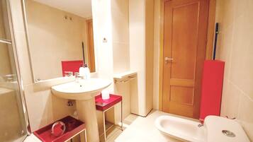 Un baño con lavamanos, inodoro y zona de ducha.