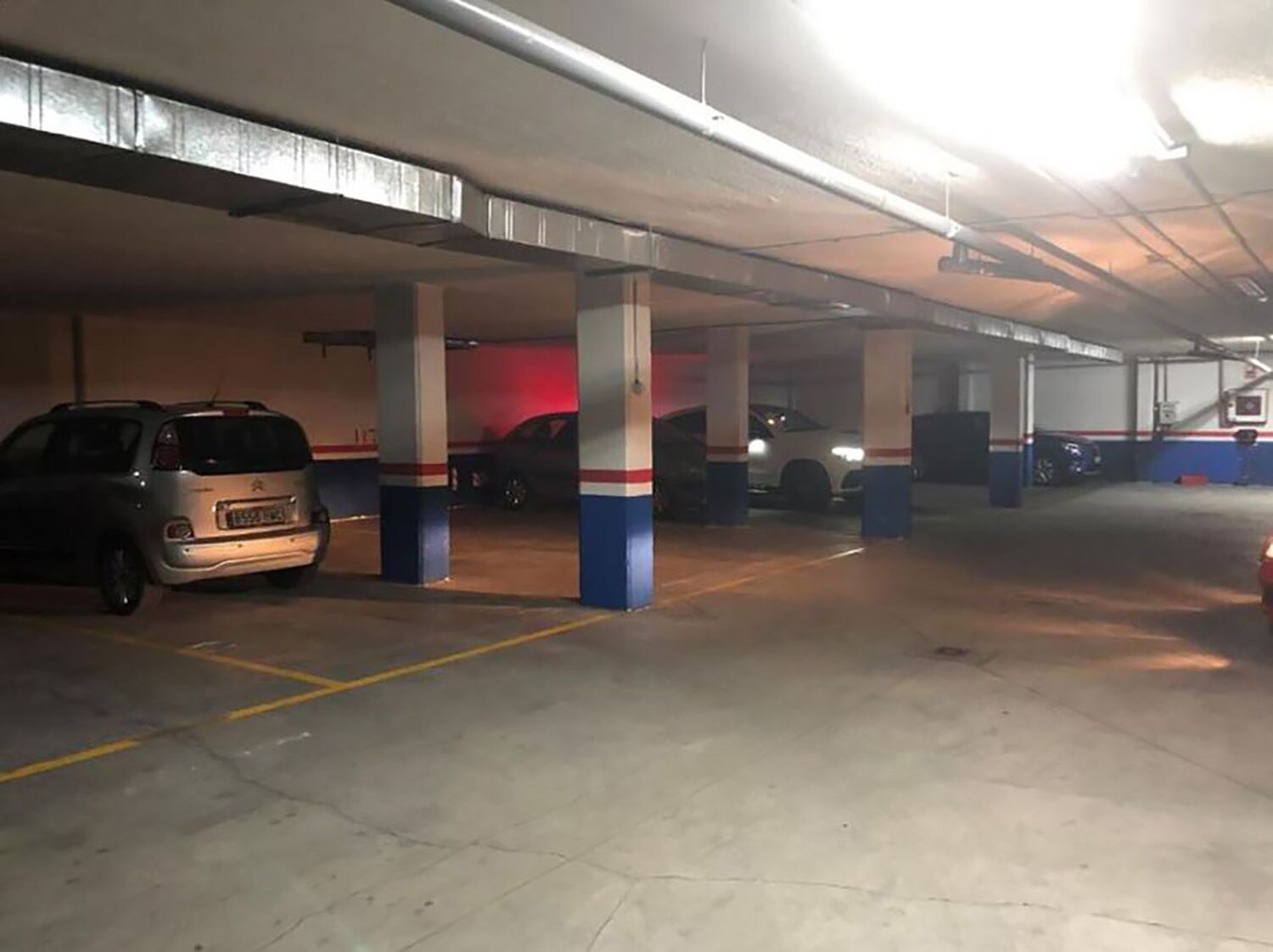 A multi-level parking garage with concrete pillars and yellow parking lines.
