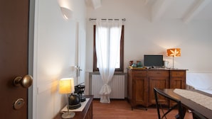 Une chambre d’hôtel avec un bureau en bois, un lit, une télévision, une lampe et un radiateur.
