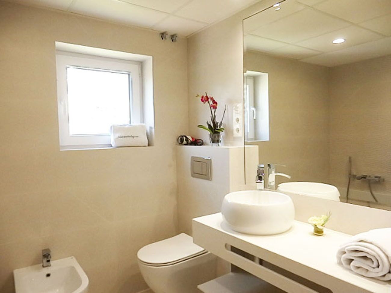 A modern bathroom with a toilet, bidet, and a sink with a mirror.