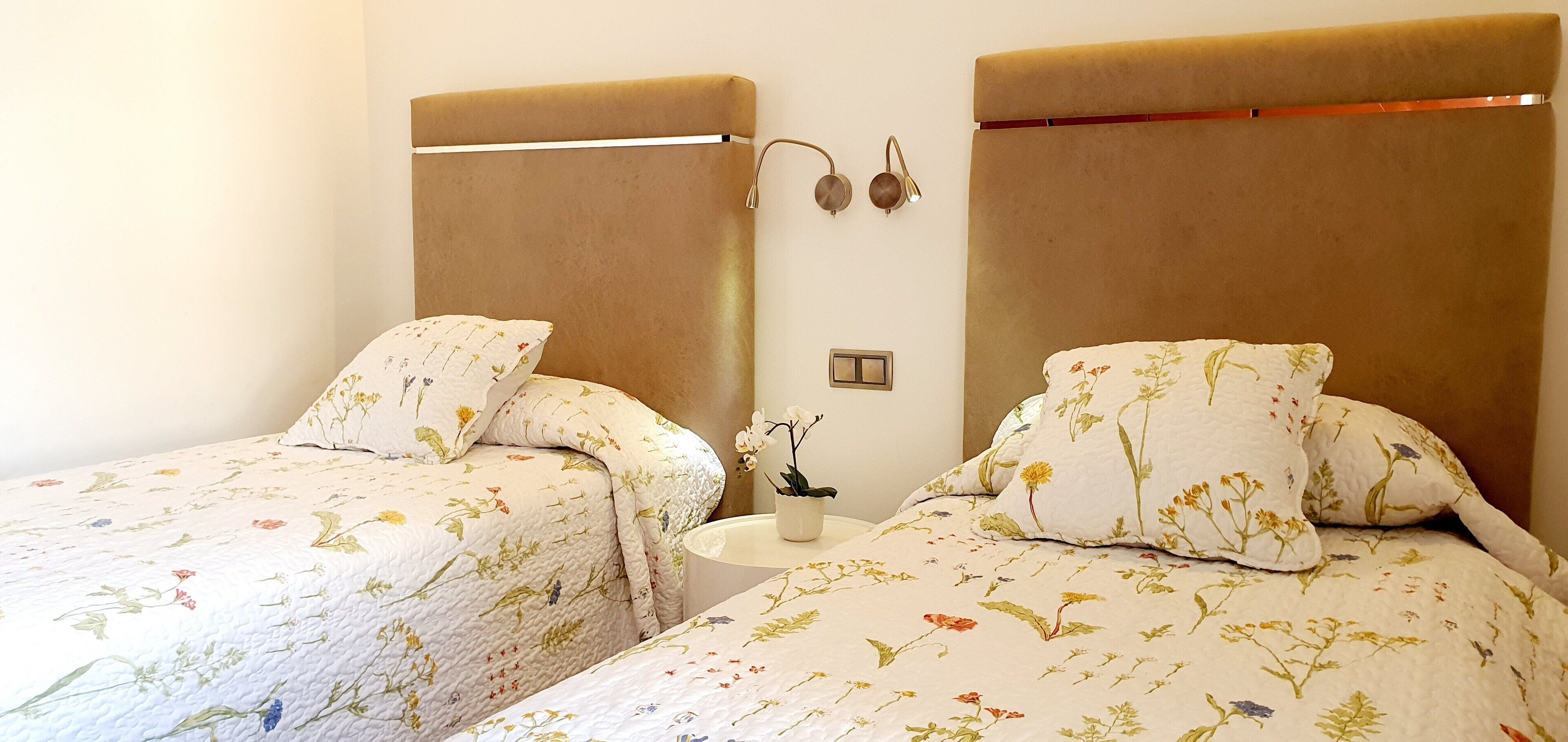 A double room with two beds, each with floral-patterned bedding and headboards.