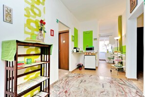 Eine Hotelhalle mit einem Holzbüro, einer grünen Wand mit einem großen, gelben Design, einer Küchenzeile und einem Essbereich mit einem Wagen.