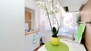 Eine moderne Küche mit einem Gasherd, einer Spüle und einem gelben Orchideenstrauß auf einer grünen Matte.