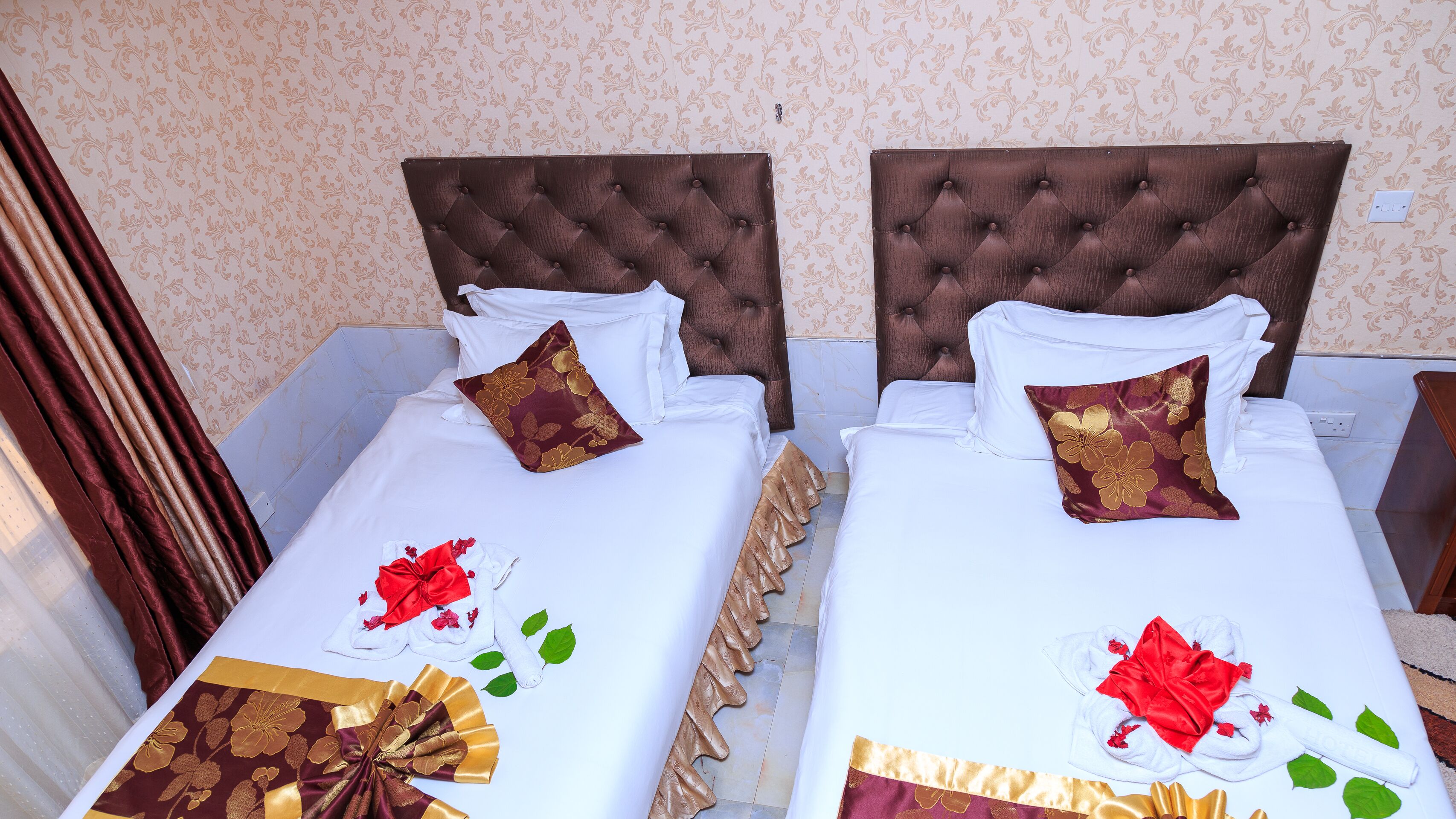 Two beds with brown headboards, white bedding, and decorative pillows.