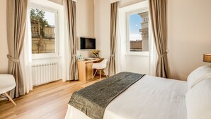 A hotel room with a bed, a desk with a chair, a TV, and large windows with curtains. - Dopodomani Suite (Rome)