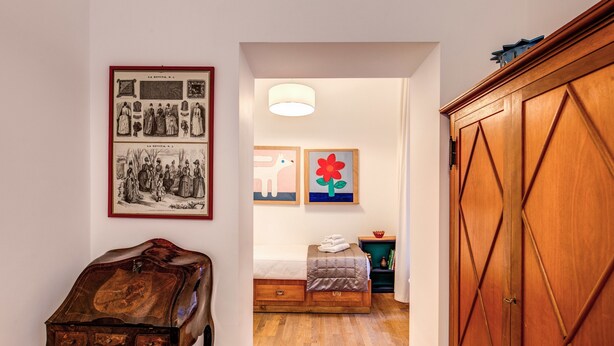 A hallway with a wooden table, a bed with a headboard, and artwork on the walls. - Dopodomani Suite (Rome)