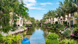 A serene hotel courtyard with a central water feature, surrounded by lush greenery and thatched-roof structures. - Koi Resort and Spa Hoi An (Da Nang)