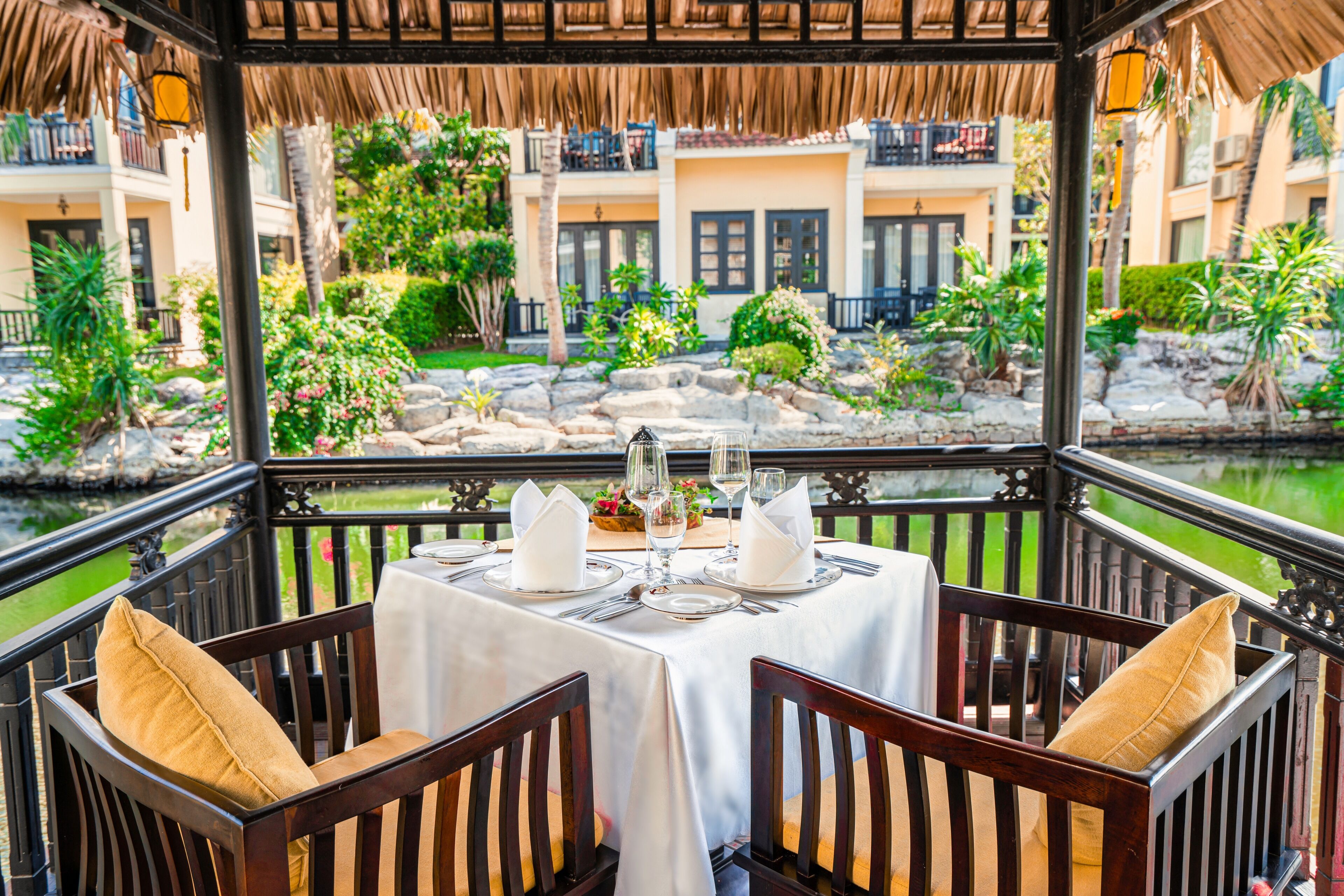 A dining area with a table set for four, overlooking a garden and water feature.