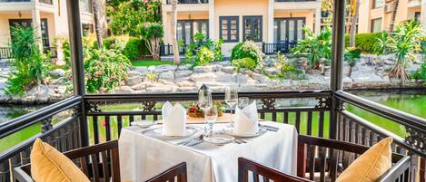 A dining area with a table set for four, overlooking a garden and water feature.