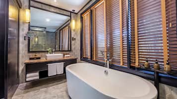 A modern bathroom with a freestanding bathtub, a large mirror, and wooden blinds.