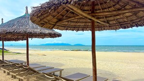 Uma praia com espreguiçadeiras e toldos de palha.