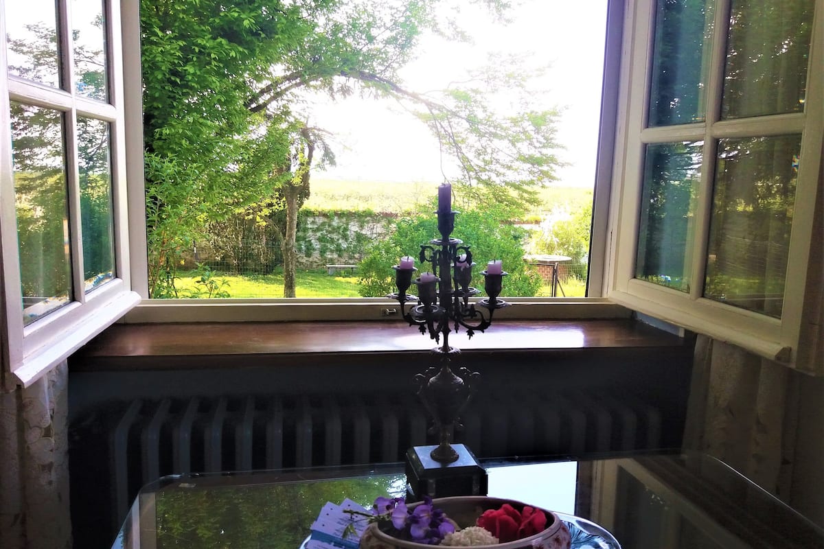 A table with a glass top, a candle holder, and a bowl with flowers.