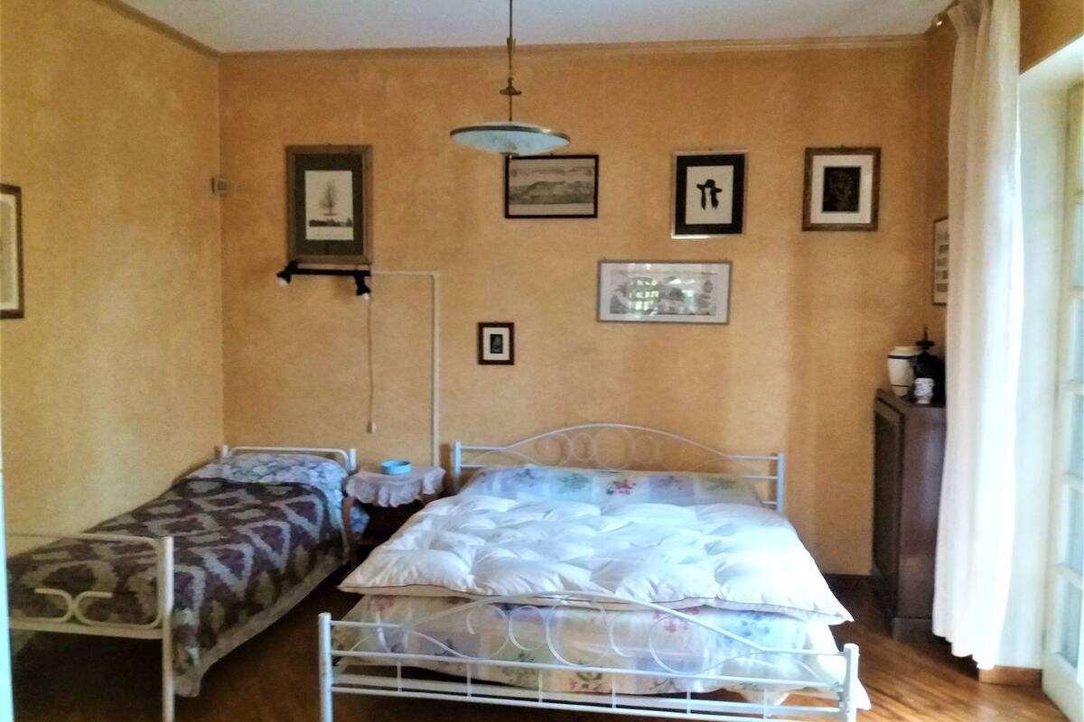 A bedroom with two single beds, a bedside table with a lamp, and a dresser.