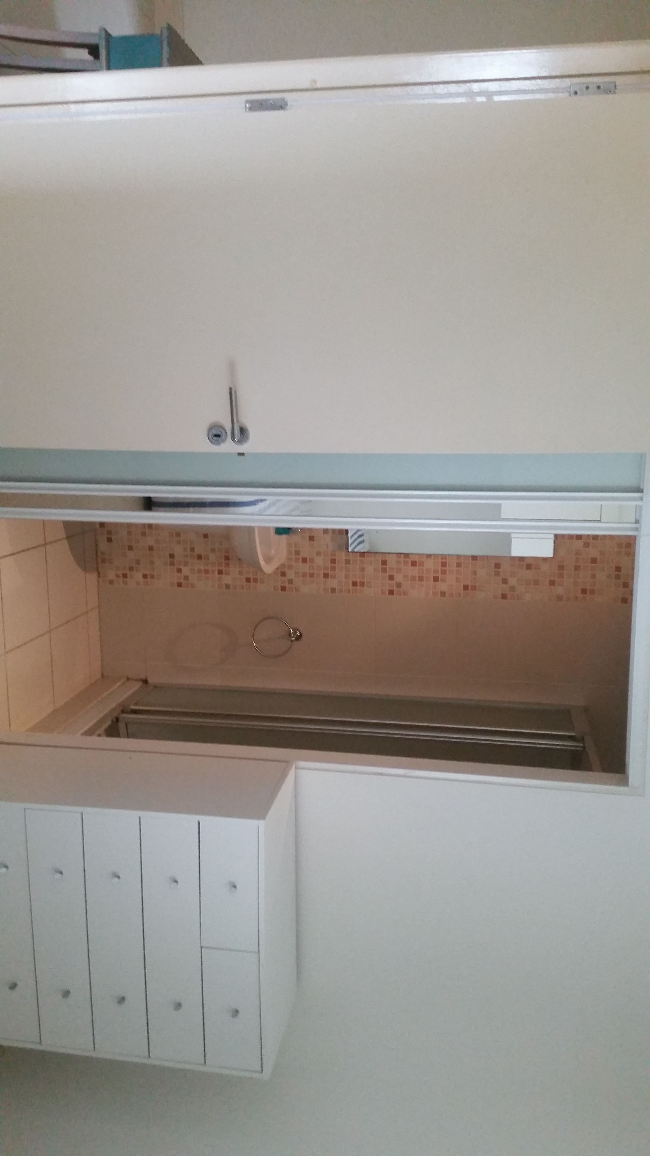 A kitchen with a tiled backsplash, a sink, and a cabinet with multiple drawers.