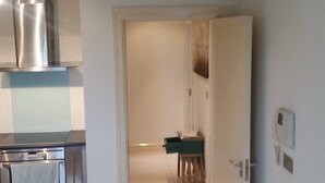 Una cucina con elettrodomestici in acciaio inossidabile, pavimento piastrellato e un corridoio che conduce a una zona pranzo.