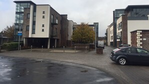 Un edificio moderno con facciate in mattoni e vetro, un'area di parcheggio e una strada bagnata.