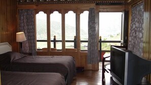 A room with a bed, a television, and a window with a view of the outdoors. - Dewachen Resort (Paro)