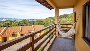 A balcony with a hammock, a view of the sea, and buildings in the background. - Águas de Palmas Resort (Governador Celso Ramos)