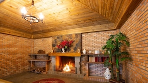 A cozy room with a fireplace, a wooden ceiling, and a brick wall. - Águas de Palmas Resort (Governador Celso Ramos)