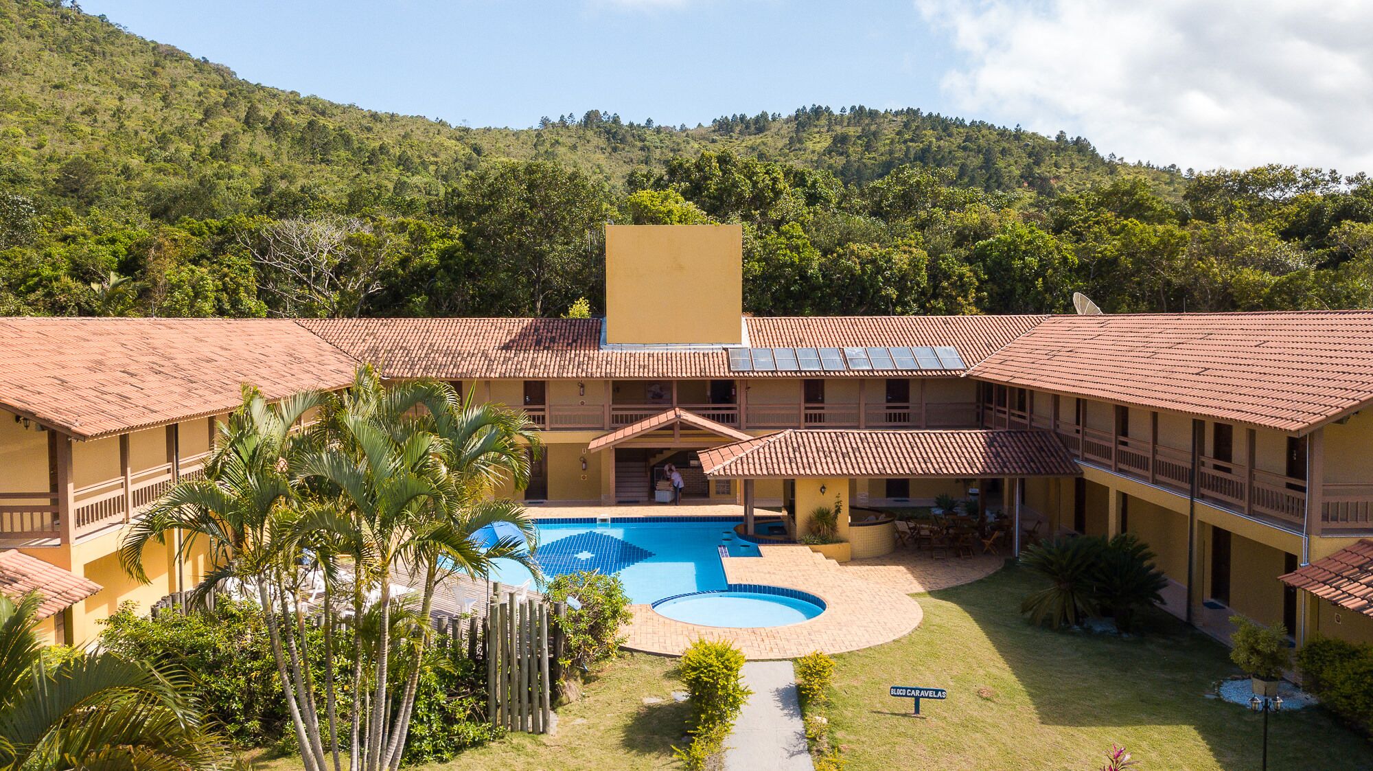 Um resort com piscina, vários edifícios e montanhas ao fundo.