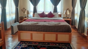 Une chambre à coucher avec un lit en bois, deux tables de chevet, un radiateur et un tapis à motifs.