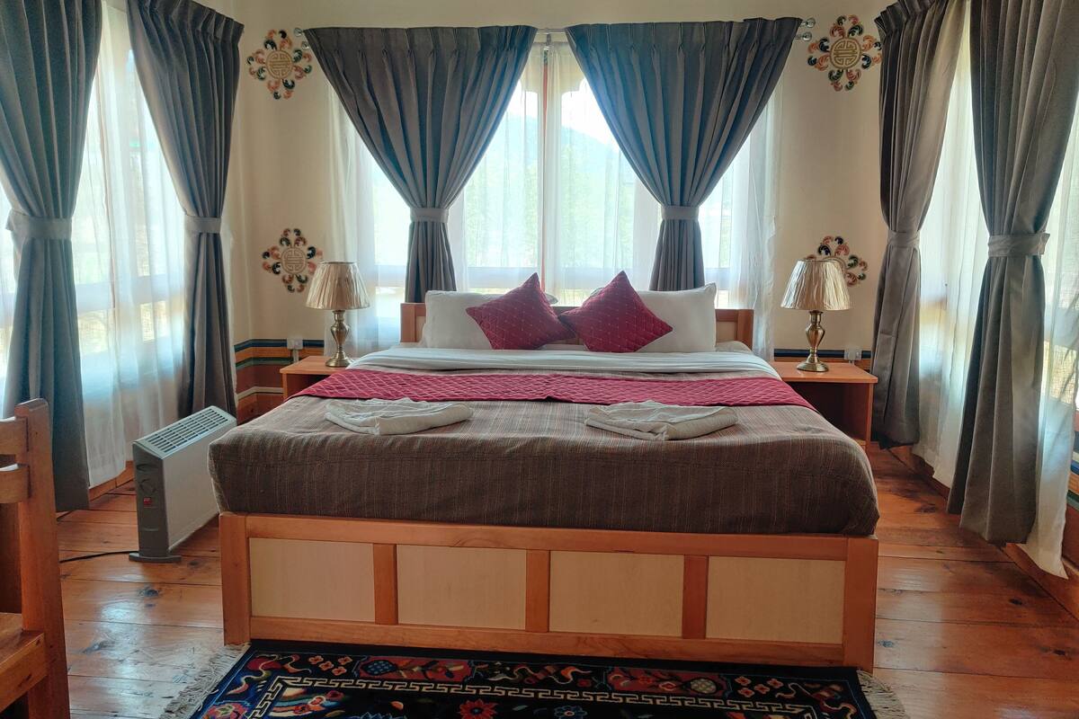 Une chambre à coucher avec un lit en bois, deux tables de chevet, un radiateur et un tapis à motifs.