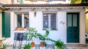 A white building with a green door, windows, and a small balcony with potted plants.