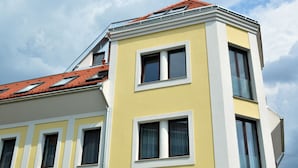 A yellow building with multiple windows and a red-tiled roof. - Toldi Apartments (Pecs)