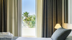 A hotel room with a bed, a lamp, and curtains.
