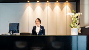A reception desk with a modern design, a potted plant, and a wall-mounted device.