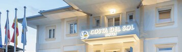Het uiterlijk van Hotel Costa del Sol met een bord, meerdere ramen en vlaggen.