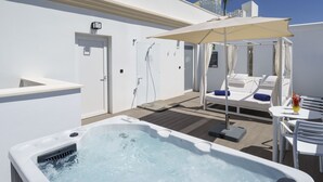 A rooftop pool area with a hot tub, lounge chairs, and umbrellas.