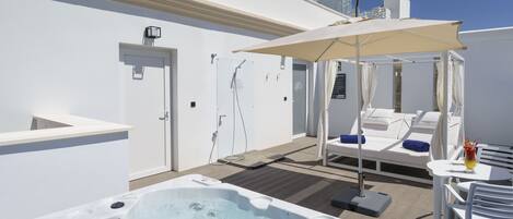 A rooftop pool area with a hot tub, lounge chairs, and umbrellas.