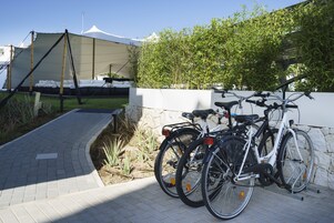 Een verhard pad dat leidt naar een witte tentstructuur, met twee fietsen tegen een muur geleund.