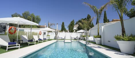 Una piscina al aire libre de temporada, sombrillas, tumbonas