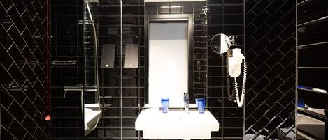 A modern bathroom with a white sink, two blue glasses, a hairdryer, and a towel ring.
