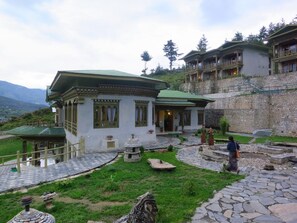Un edificio tradicional con techo verde, paredes de piedra y un patio con fuente de piedra.
