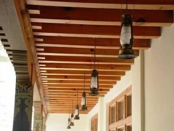 A corridor with wooden beams and hanging lanterns.